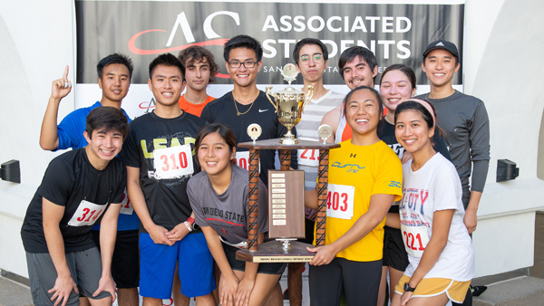 students with a trophy in front of Associated Students banner